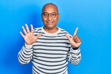 Middle age latin man wearing casual clothes and glasses showing and pointing up with fingers number seven while smiling confident and happy.
