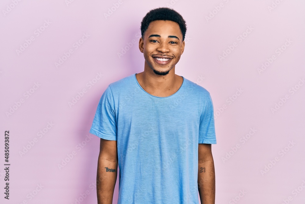 Young african american man wearing casual blue t shirt with a happy and cool smile on face. lucky person. Young african american man wearing casual blue t shirt with a happy and cool smile on face. lucky person.