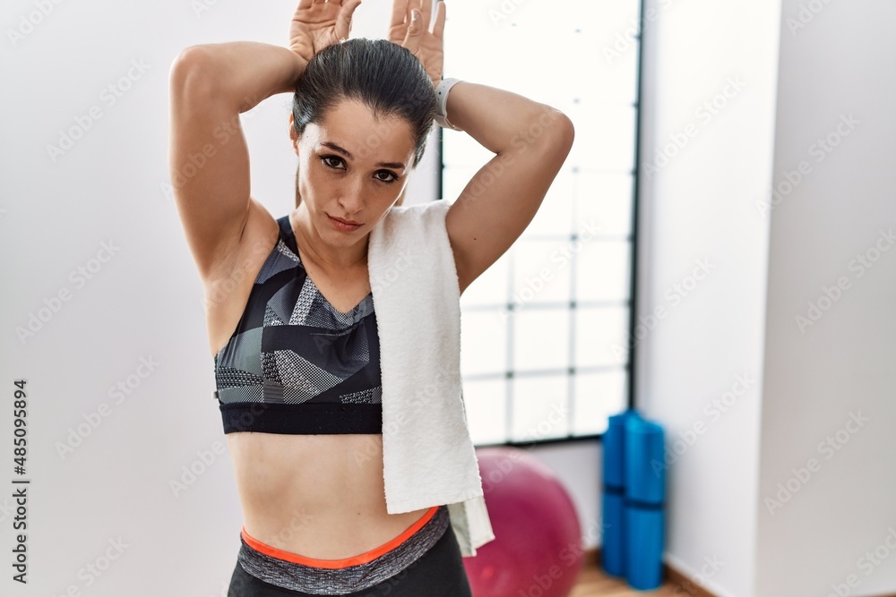 Young brunette woman wearing sportswear and towel at the gym doing bunny ears gesture with hands palms looking cynical and skeptical. easter rabbit concept.