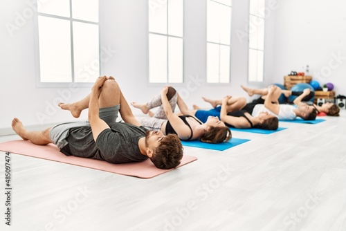 Group of young hispanic people concentrate training yoga at sport center.