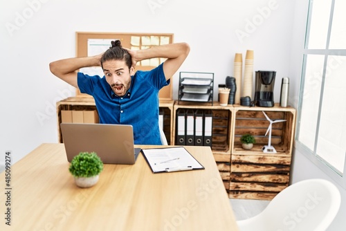 Handsome hispanic man working with laptop celebrating success at the office