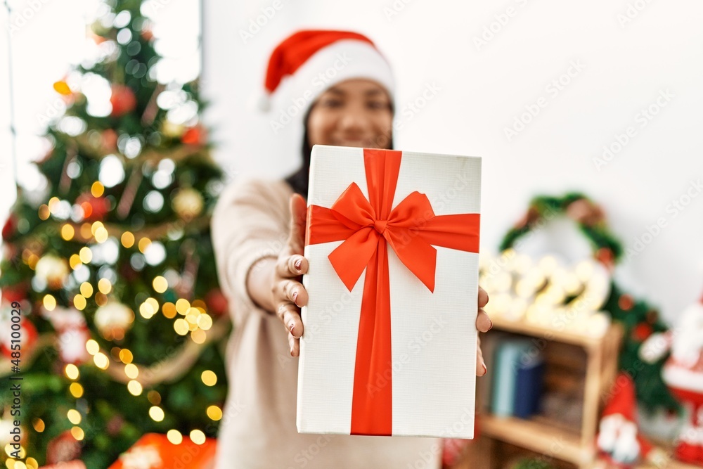 Hispanic brunette woman holding christmas present at home Hispanic brunette woman holding christmas present at home
