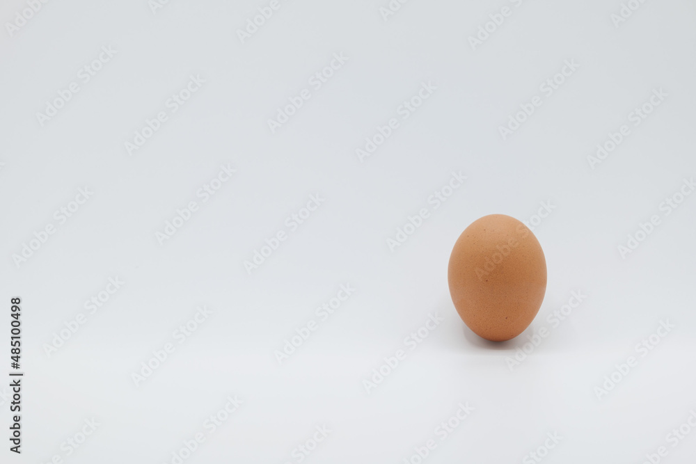 A brown egg placed upside down on a plain white background.