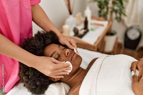 Young african american woman having cleaning face treatment at beauty center