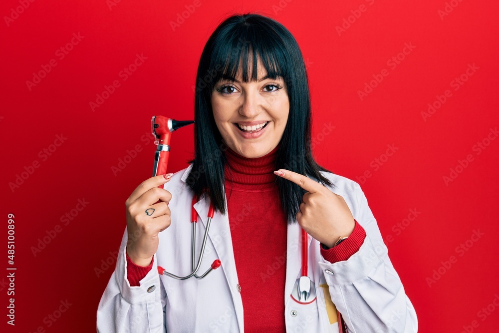Young hispanic doctor woman holding medical model smiling happy pointing with hand and finger Young hispanic doctor woman holding medical model smiling happy pointing with hand and finger