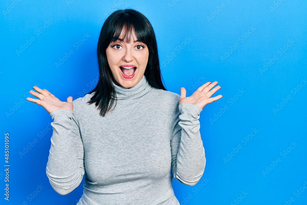 Young hispanic woman wearing casual clothes celebrating crazy and amazed for success with arms raised and open eyes screaming excited. winner concept Young hispanic woman wearing casual clothes celebrating crazy and amazed for success with arms raised and open eyes screaming excited. winner concept