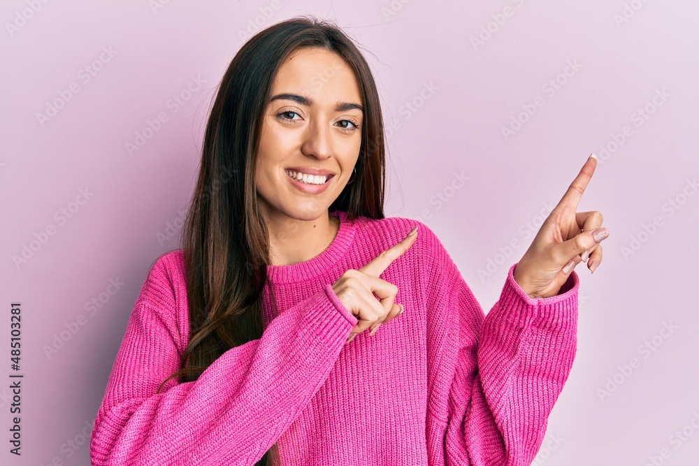 Young hispanic girl wearing casual clothes smiling and looking at the camera pointing with two hands and fingers to the side. Young hispanic girl wearing casual clothes smiling and looking at the camera pointing with two hands and fingers to the side.