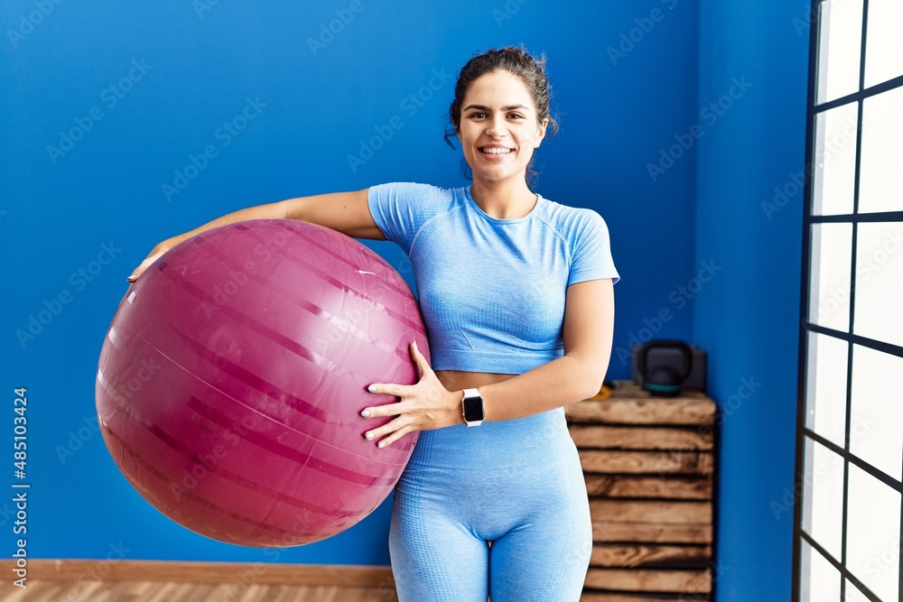 Young latin woman wearing sportswear holding fit ball at sport center Young latin woman wearing sportswear holding fit ball at sport center
