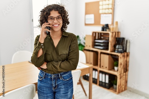 Young hispanic woman smiling confident talking on the smartphone at office