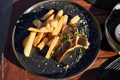  Plate of fish and chips potatoes on wooden surface photo