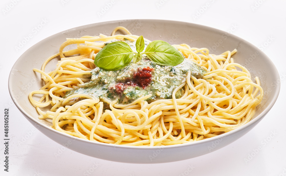 Plate of italian spaghetti pasta with pesto sauce over white isolated background Plate of italian spaghetti pasta with pesto sauce over white isolated background