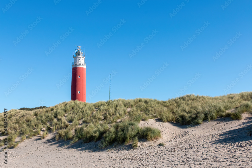 The Texel lighthouse sticking out above the dunes in the Netherlands with a clear blue sky on a beautiful day
