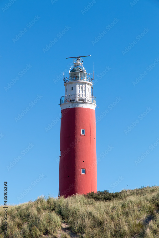 The Texel lighthouse sticking out above the dunes in the Netherlands with a clear blue sky on a beautiful day