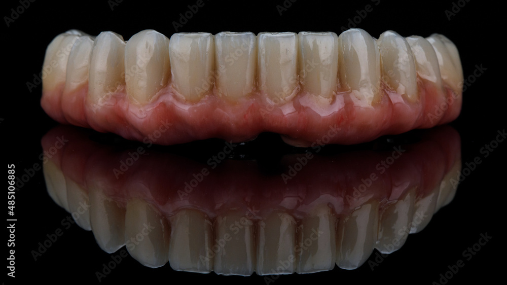 ceramic prosthesis with pink gum for the lower jaw, on black glass and creative reflection ceramic prosthesis with pink gum for the lower jaw, on black glass and creative reflection