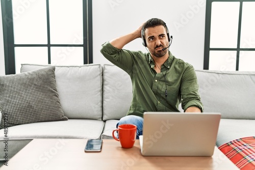 Εκτύπωση καμβά Young hispanic man with beard wearing call center agent headset working from home confuse and wondering about question