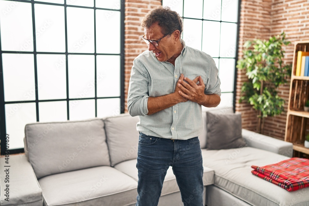 Middle age man touching chest suffering heart attack at home