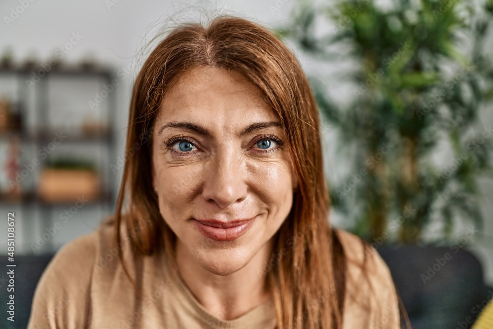 Obraz premium Middle age caucasian woman smiling happy sitting on the sofa at home.
