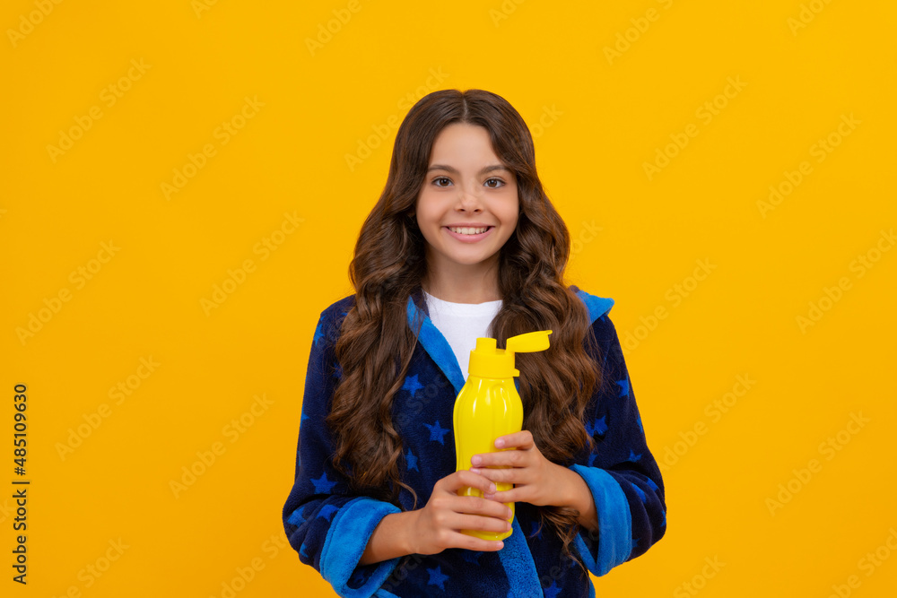 Happy girl child holding water bottle in homewear yellow background, thirst Happy girl child holding water bottle in homewear yellow background, thirst