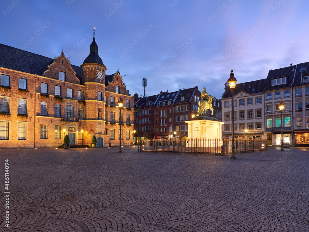 Fototapeta premium Town hall in the old town of Dusseldorf in Germany. Beautifully illuminated Central Square with the Johann Wilhelm II monument at the blue hour before dawn.