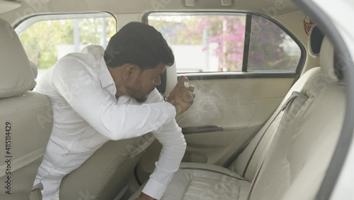 Indian cab or taxi driver sanitaising or adding freshener to back seat before customer entering car - concept of hygiene, ransportation service and fragrance. photo