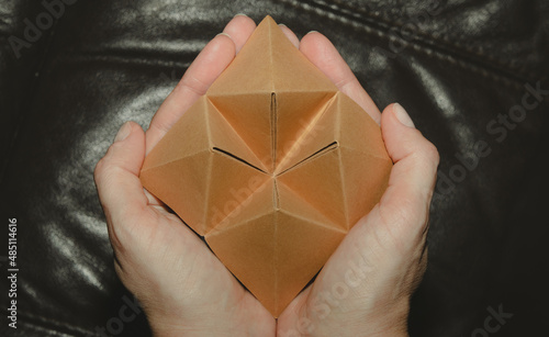Photos Female hands holding a paper fortune teller with blank wings.