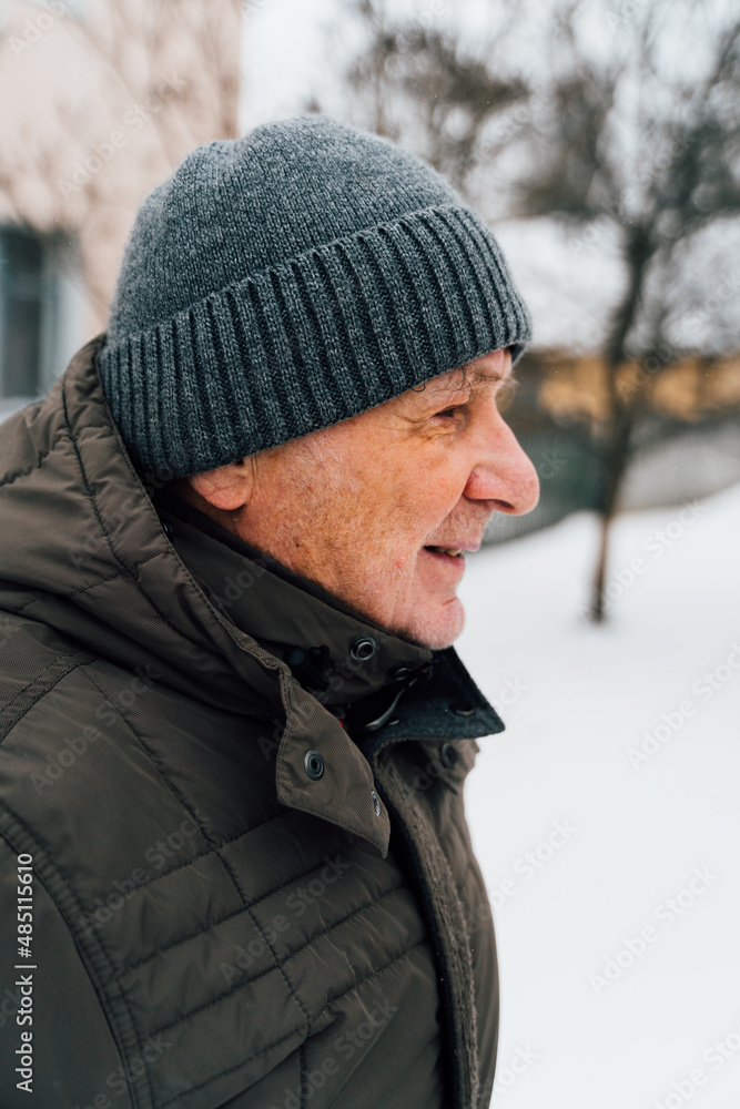 Close-up portrait of delighted old man in warm clothes is standing outdoors and laughing Close-up portrait of delighted old man in warm clothes is standing outdoors and laughing