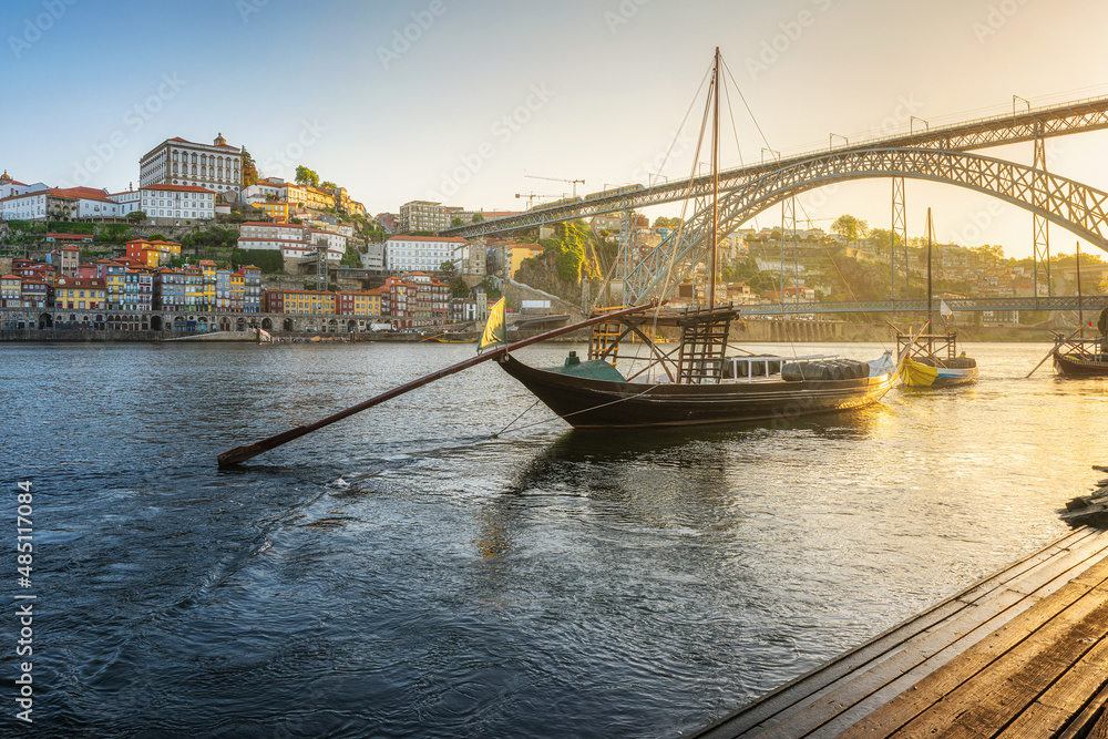 Porto, Portugal. Sunrise view of trditional boats rabelo with Dom Luis bridge on Douro river with old town of Oporto city