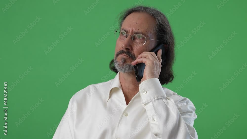 Bearded man with glasses holding smarphone in conversation on a green screen chroma key background. Bearded man with glasses holding smarphone in conversation on a green screen chroma key background.