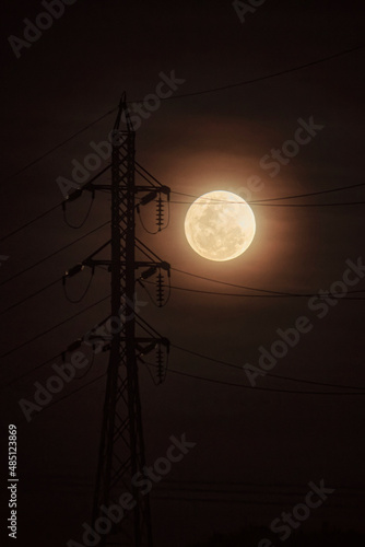 lua cheia alaranjada e com fog ou neblina com torre eletrica de energia com luz natural photo