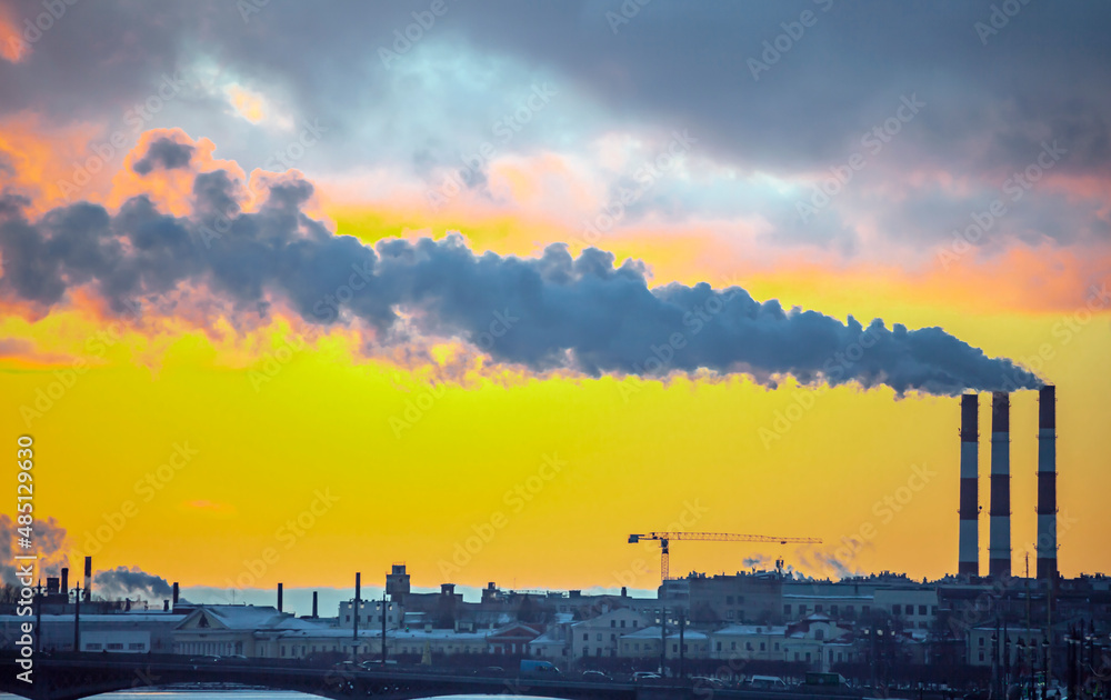 Obraz premium Smoke from industrial chimneys and a heavenly landscape at sunset.