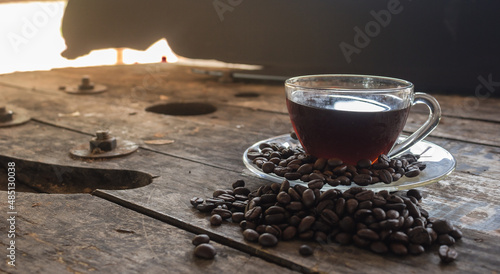 Coffee beans and coffee mugs on wooden floor and black background