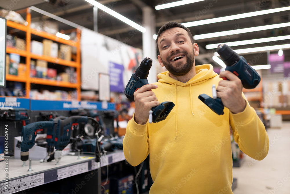 a customer fooling around with two out of hand screwdrivers in the tool section of a hardware store