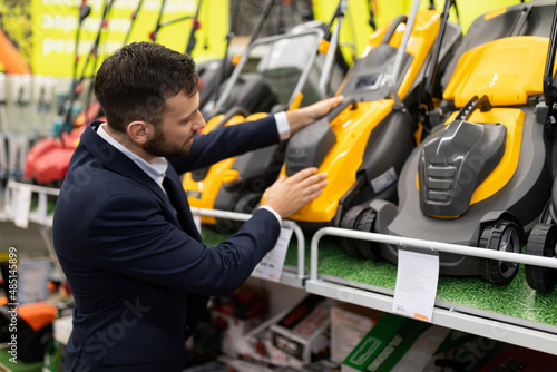 the buyer is determined with the choice of a lawn mower in a garden equipment store