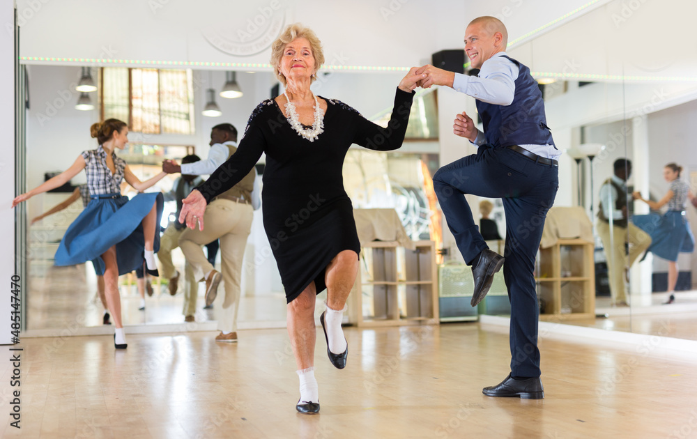 Man and elderly woman performing jazz dance in dancing room Man and elderly woman performing jazz dance in dancing room