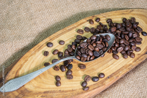 on the burlap-covered table. Coffee grains on a wooden plate. metal spoon
