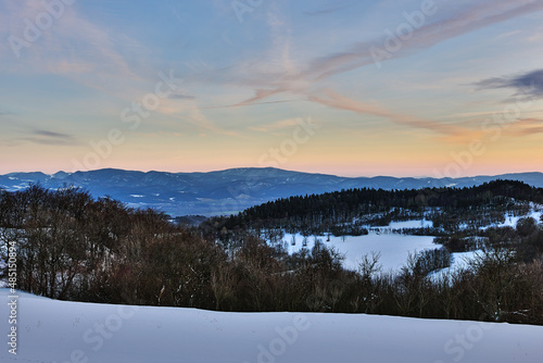 Winter snowy mountain landscape at dusk. Shortly after sunset. With forest and hills. Sky in blue oange. Nature background, wallpaper. Protected area Vrsatec, Slovakia. © Robert Adami