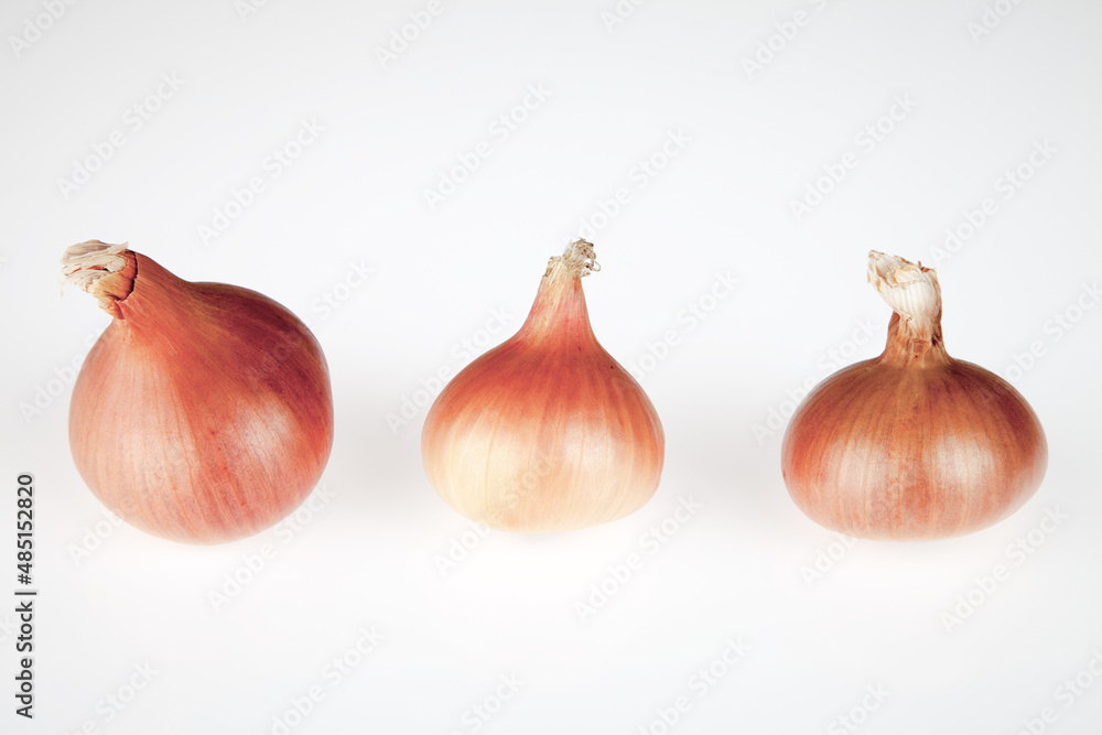 Obraz premium Three onions on a white background