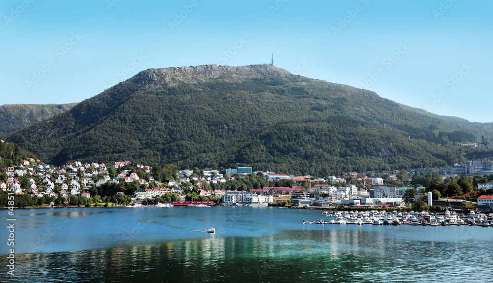 View of the beautiful colored houses of the city of Bergen on the shore of the North Sea against the background of Mount Ulriken on a clear sunny day, Norway. Travel landscape sights of Europe. View of the beautiful colored houses of the city of Bergen on the shore of the North Sea against the background of Mount Ulriken on a clear sunny day, Norway. Travel landscape sights of Europe.