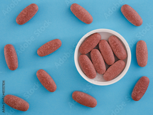 Organic red yeast rice tablets in a cap with other organic red yeast rice tablets around them photo