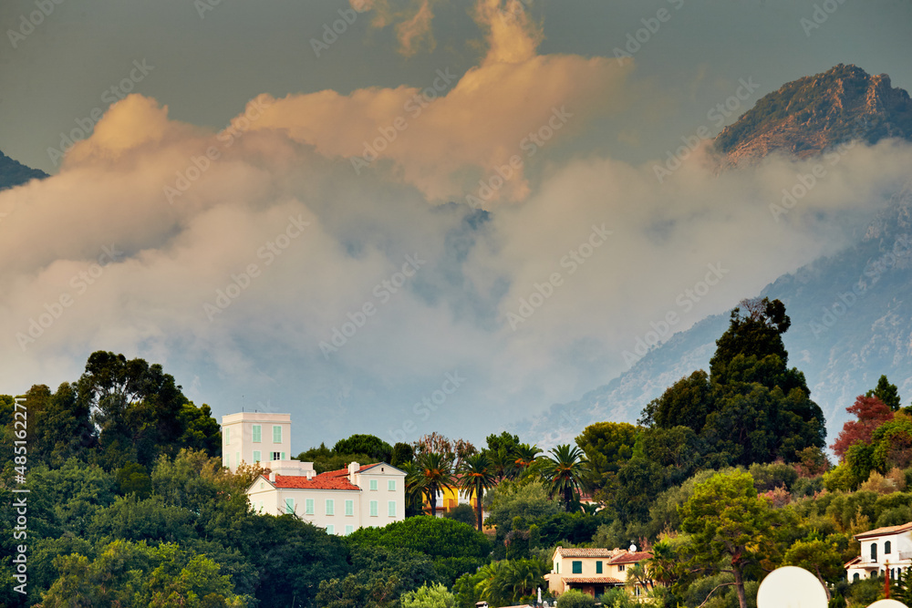 View of the mountains of Italy at sunset, Ventimiglia at sunset through the villa and forest, orange and pink clouds