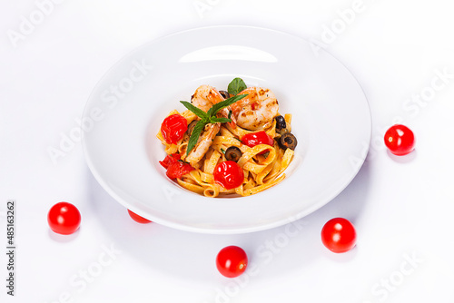 Special shrimp pasta dish made by restaurant chef with tomatoes and olives shot on white background