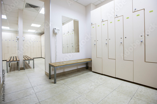 wide frame with a white locker room with wooden cabinets and benches