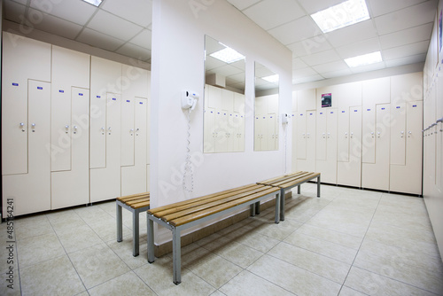 wide frame with a white locker room with wooden cabinets and benches