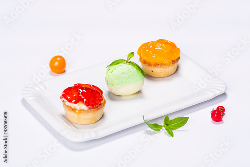 three beautifully colored cakes on the plate and decoration on white background