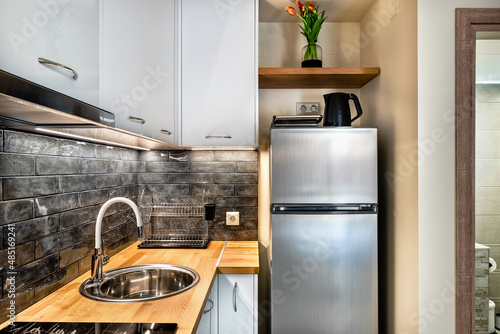 Modern kitchenette corner in grey colors. Equipped with big fridge, electrical kettle, toaster, water sink. photo