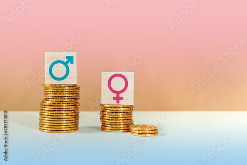 Male and female symbols on piles of coins. Gender pay equality concept. photo