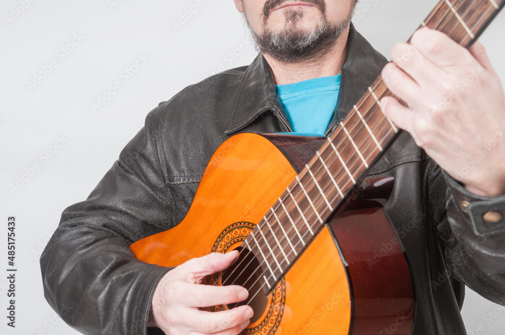 Obraz premium Man in leather jacket playing on acoustic guitar close up