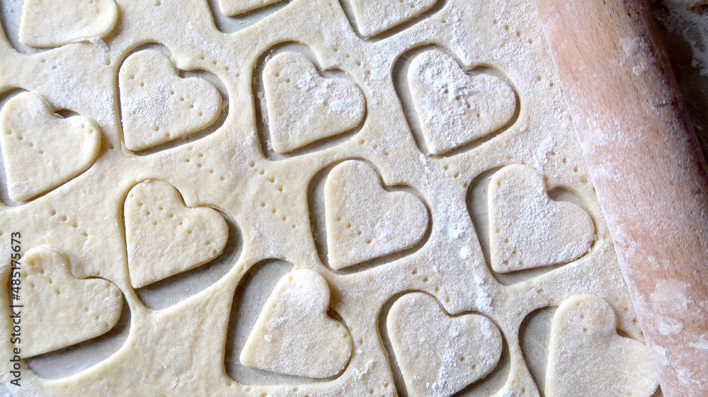 Hearts in soft rolled dough with a wooden rolling pin for valentine's day