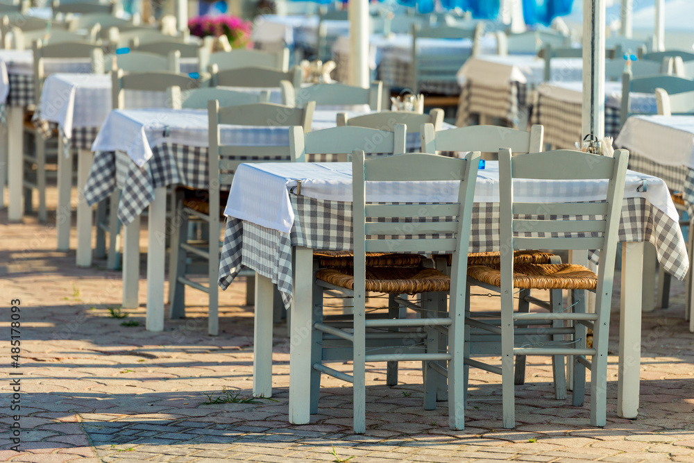Range of wooden table and white chair for relaxation at restaurant near sea