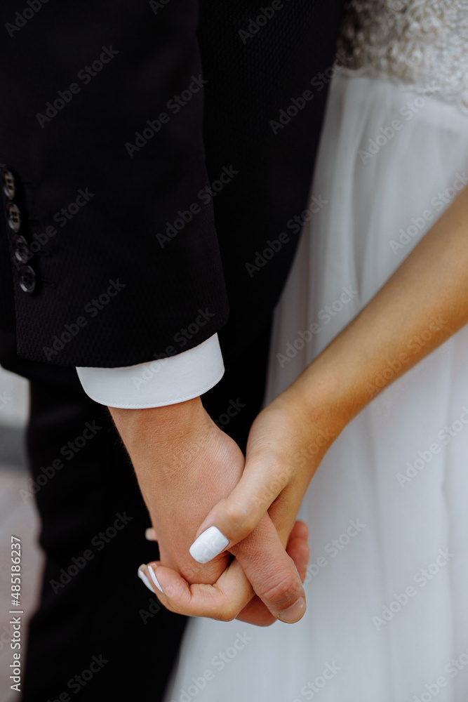 Obraz premium Closeup of loving couple holding hands while walking at sunset